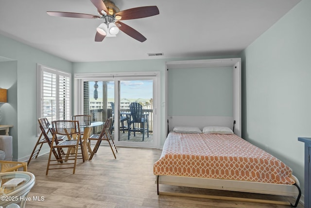 bedroom with wood finished floors, visible vents, baseboards, a ceiling fan, and access to outside