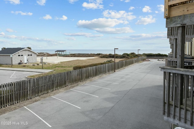 uncovered parking lot featuring a water view and fence