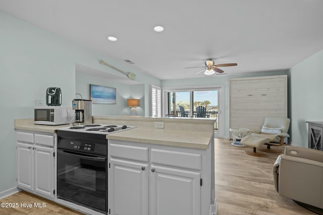 kitchen featuring white cabinets, a peninsula, black / electric stove, and white microwave