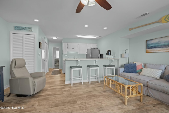 living area with ceiling fan, recessed lighting, visible vents, baseboards, and light wood-type flooring