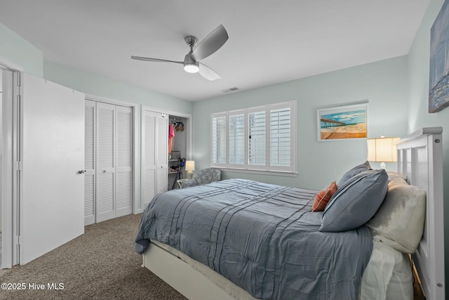 bedroom featuring carpet floors, ceiling fan, visible vents, and two closets