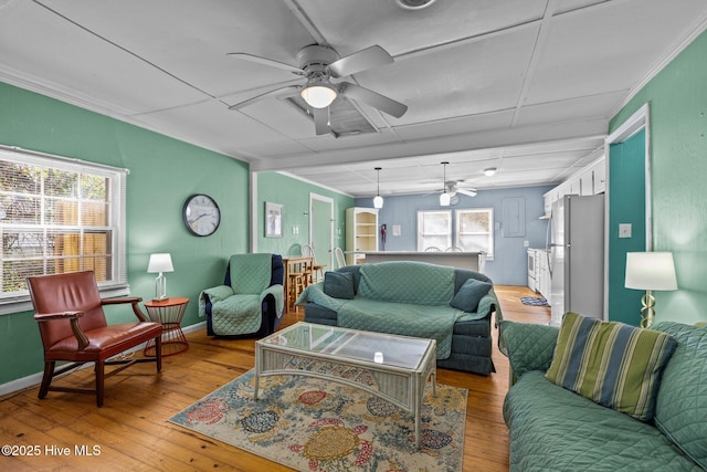 living area with a healthy amount of sunlight, light wood-style flooring, baseboards, and a ceiling fan