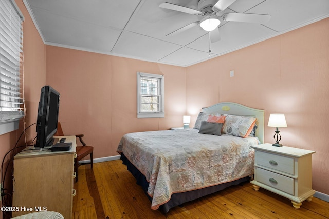 bedroom featuring a ceiling fan, baseboards, crown molding, and hardwood / wood-style floors