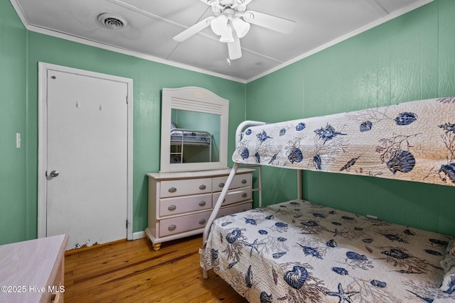 bedroom with hardwood / wood-style floors, ceiling fan, visible vents, and crown molding