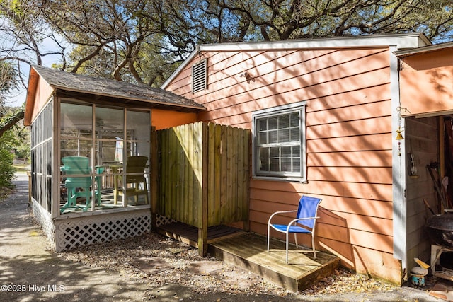 view of outdoor structure featuring a sunroom and fence