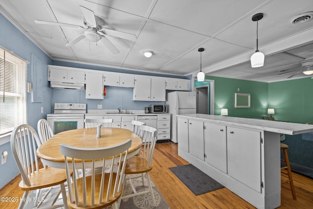 kitchen featuring light countertops, white appliances, visible vents, and under cabinet range hood