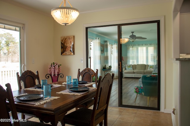dining room with light tile patterned floors, ceiling fan with notable chandelier, and ornamental molding