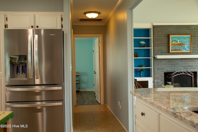 kitchen featuring visible vents, white cabinets, stainless steel fridge, crown molding, and tile patterned flooring