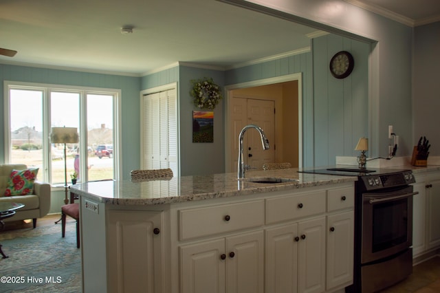 kitchen featuring light stone counters, electric range, crown molding, white cabinets, and a sink