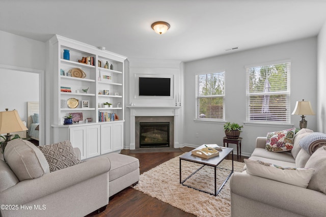 living area featuring dark wood-type flooring, a fireplace with flush hearth, visible vents, and baseboards