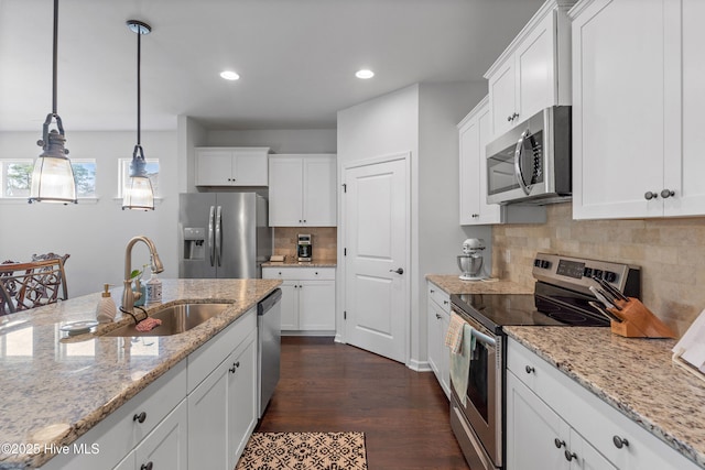 kitchen featuring dark wood-style floors, pendant lighting, stainless steel appliances, white cabinets, and a sink