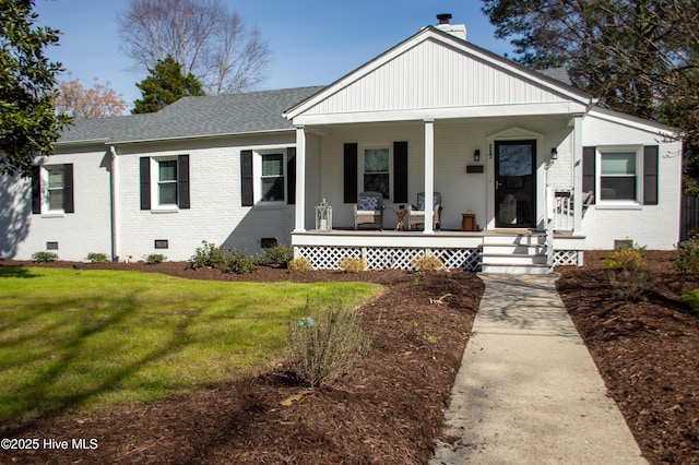 view of front facade featuring a shingled roof, a porch, brick siding, and crawl space