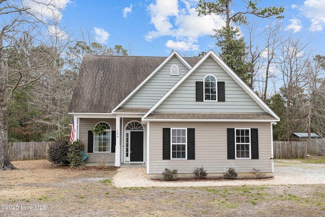 traditional-style house featuring a shingled roof and fence