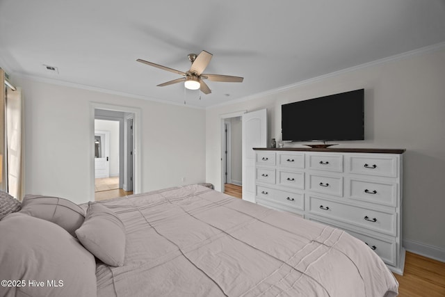 bedroom with baseboards, light wood finished floors, visible vents, and crown molding