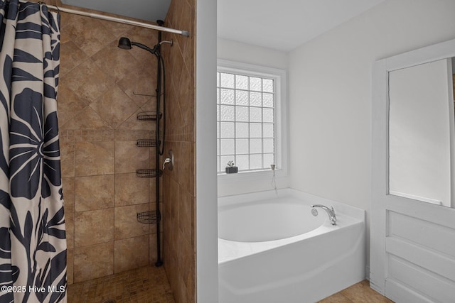 bathroom with a garden tub and tiled shower