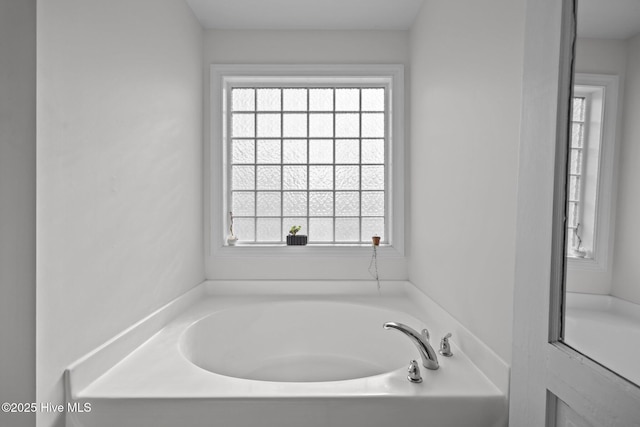 bathroom featuring a garden tub and a healthy amount of sunlight