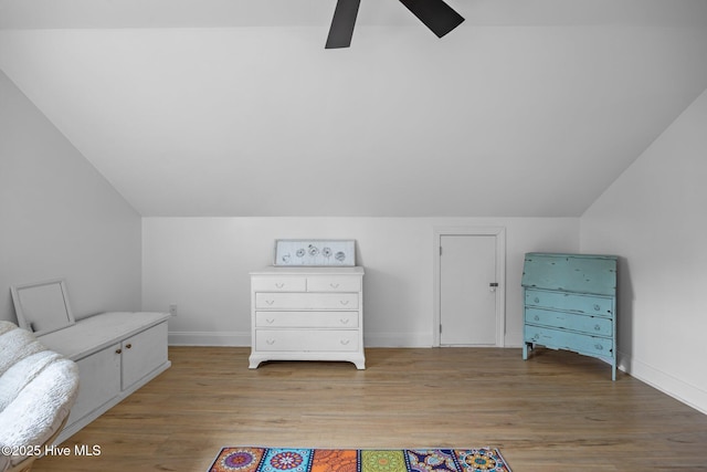 interior space featuring lofted ceiling, light wood-style flooring, baseboards, and a ceiling fan