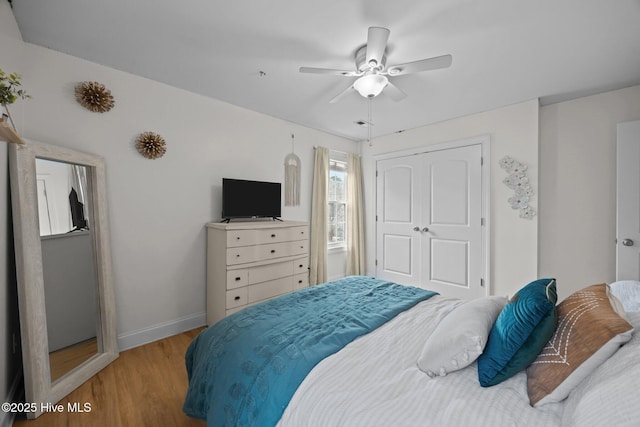 bedroom with light wood-style floors, ceiling fan, baseboards, and a closet