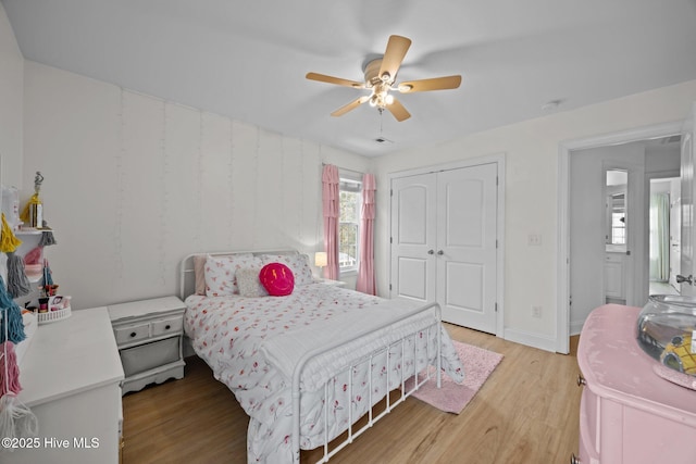 bedroom featuring light wood-style floors, ceiling fan, baseboards, and a closet