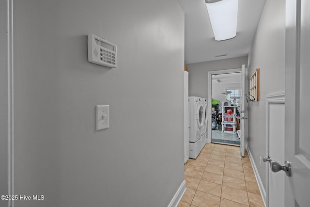 laundry area featuring light tile patterned floors, laundry area, washing machine and clothes dryer, and baseboards