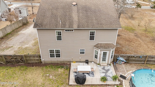 rear view of property featuring a patio, a shingled roof, and a fenced backyard