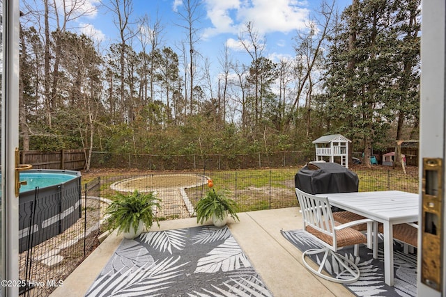 view of patio with outdoor dining space, area for grilling, a fenced backyard, and a fenced in pool