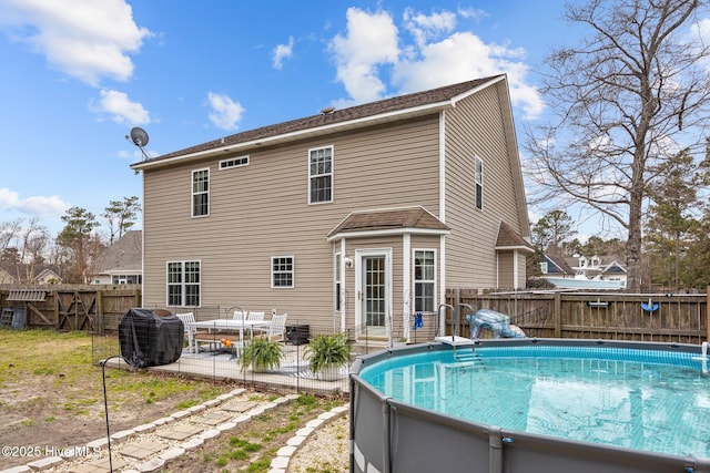 rear view of house with a fenced in pool, a patio area, and fence