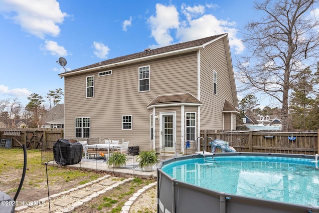 rear view of house featuring a fenced in pool, a patio area, and fence