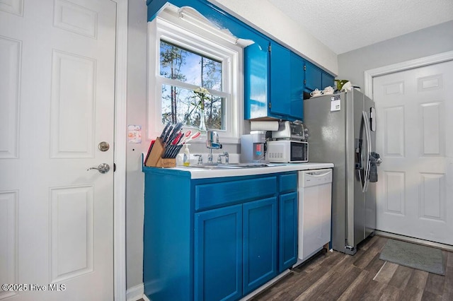 kitchen with white appliances, dark wood-type flooring, light countertops, a textured ceiling, and blue cabinetry