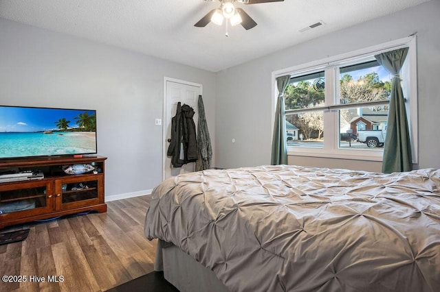 bedroom with baseboards, visible vents, ceiling fan, wood finished floors, and a textured ceiling