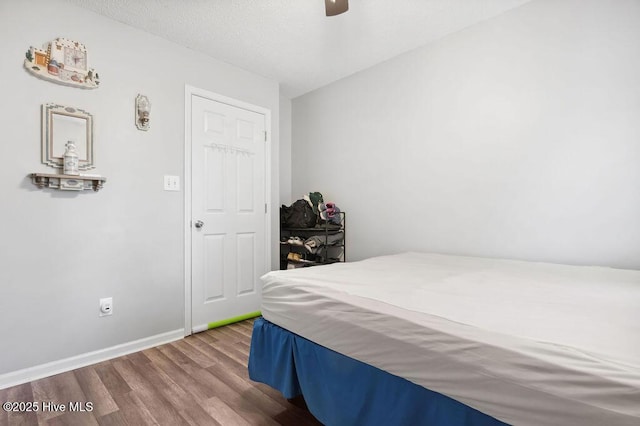 bedroom featuring ceiling fan, a textured ceiling, baseboards, and wood finished floors