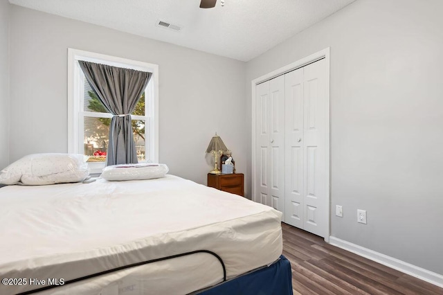 bedroom featuring dark wood-style flooring, a closet, visible vents, ceiling fan, and baseboards