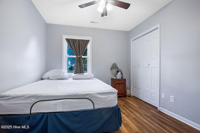 bedroom with wood finished floors, visible vents, baseboards, a ceiling fan, and a closet