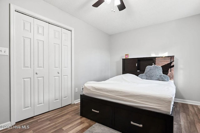 bedroom with dark wood-style floors, ceiling fan, a closet, and baseboards