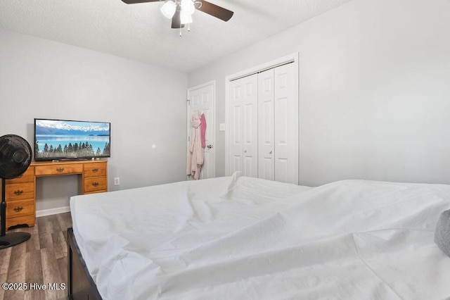 bedroom with a textured ceiling, a closet, a ceiling fan, and dark wood-type flooring