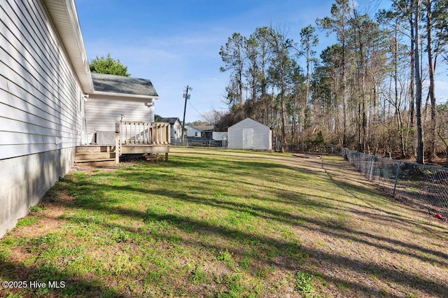 view of yard featuring an outbuilding, fence, and a wooden deck