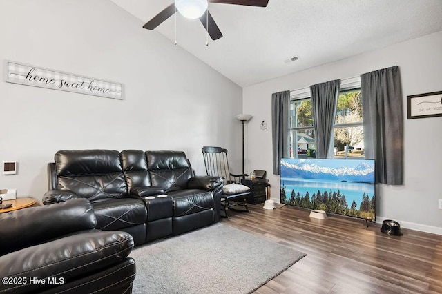 living area featuring ceiling fan, wood finished floors, visible vents, baseboards, and vaulted ceiling