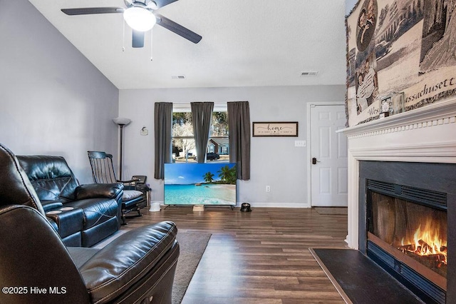 living room with baseboards, a fireplace with flush hearth, visible vents, and wood finished floors