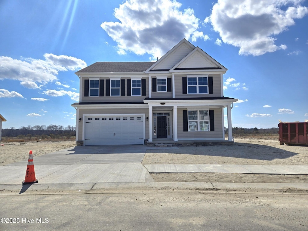 traditional-style home with a garage, covered porch, and driveway