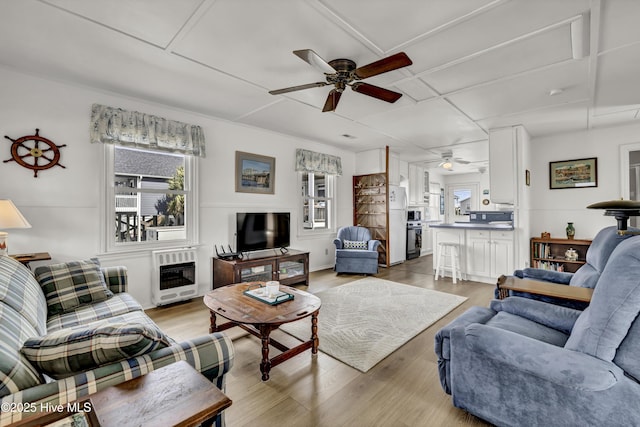 living room with heating unit, light wood finished floors, and a ceiling fan