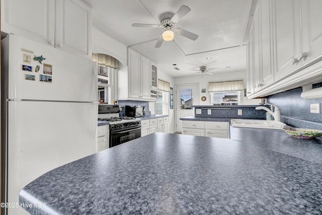 kitchen with dark countertops, range with gas stovetop, a sink, and freestanding refrigerator