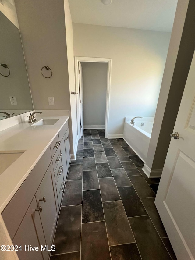 bathroom with double vanity, a sink, a bath, and baseboards