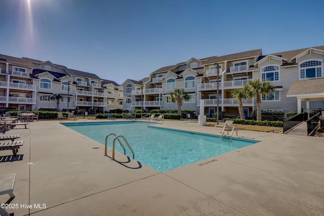 pool with a residential view, a patio, and fence