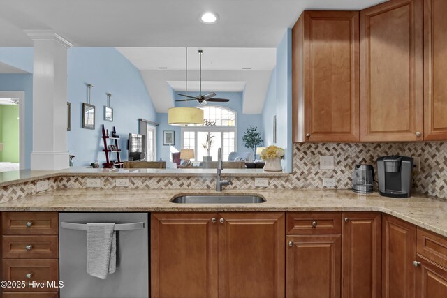 kitchen with stainless steel dishwasher, brown cabinetry, light stone countertops, and a sink