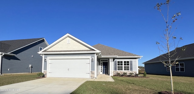 view of front of property with a garage, a shingled roof, driveway, stone siding, and a front lawn