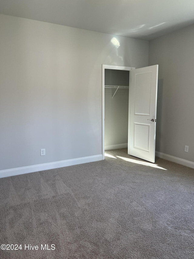 unfurnished bedroom with carpet floors, baseboards, and a closet