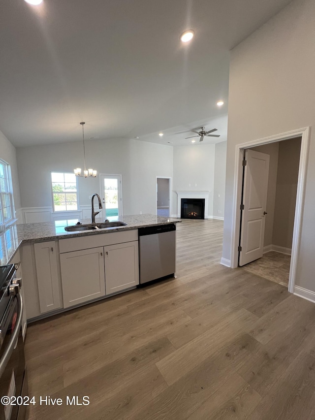 kitchen featuring stainless steel dishwasher, stove, light wood-style floors, a sink, and a lit fireplace