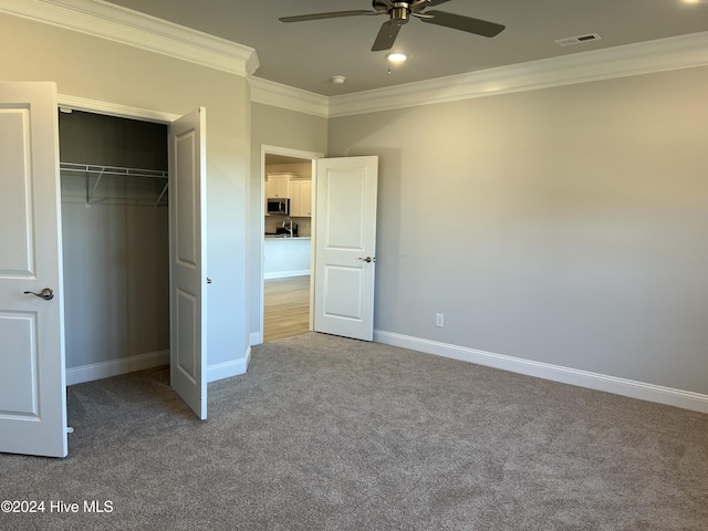 unfurnished bedroom with carpet, a closet, visible vents, ornamental molding, and baseboards