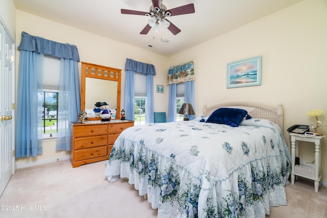 bedroom featuring visible vents, light carpet, baseboards, and a ceiling fan