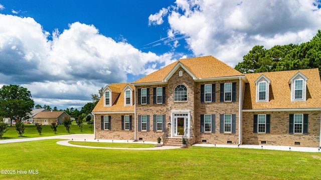 view of front facade with crawl space, a front yard, brick siding, and a shingled roof